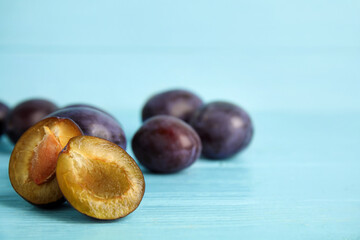 Delicious ripe plums on light blue wooden table, closeup. Space for text