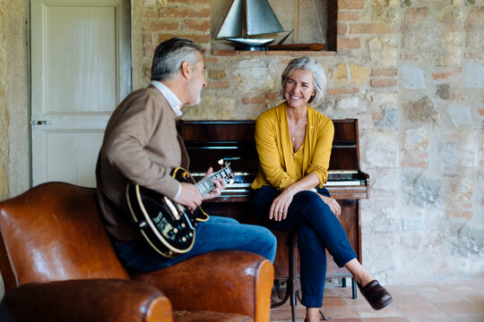 Cheerful male playing guitar for wife