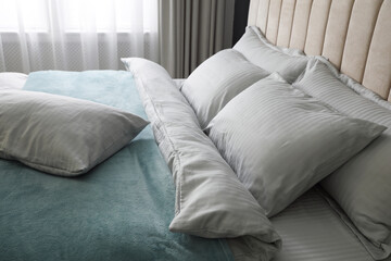 Comfortable bed with soft blanket and pillows indoors, closeup