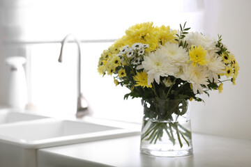 Vase with beautiful chrysanthemum flowers on countertop in kitchen, space for text. Interior design