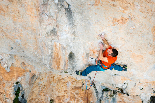 Sportive male alpinist climbing on cliff in Spain