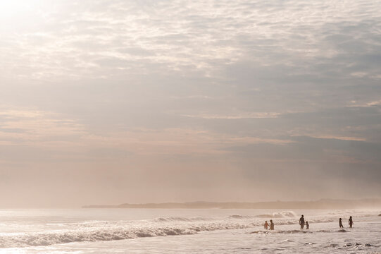 Anonymous people joyning beach at sunrise