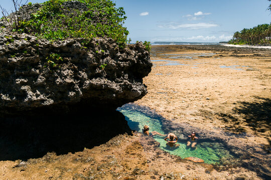 Group of friends joyning sun bath in natural pool in reef