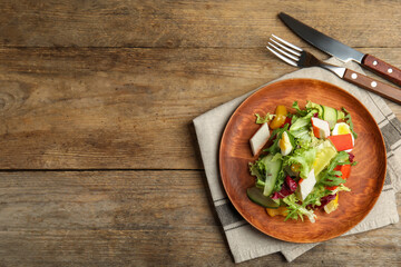Delicious salad with crab sticks and lettuce served on wooden table, flat lay. Space for text