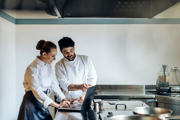 Adult chefs browsing laptop in kitchen