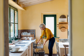 Housewife putting cups into dishwasher