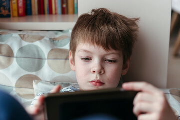 A little boy looks at the game tablet.