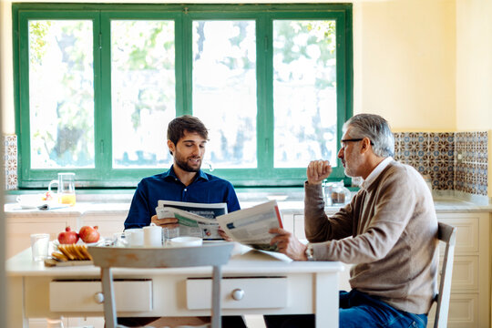 Father and son discussing news during breakfast