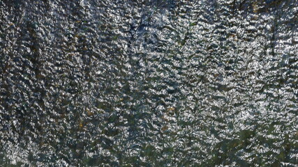 Background with running water. The gray water is flowing down the wall with the sunlight reflected for the background work. selective focus