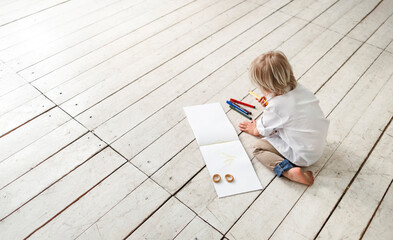 A little boy draws on the floor.
