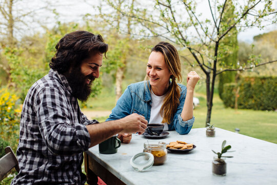 Cheerful couple snacking at table in garden