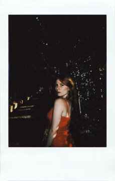 Gorgeous Redhead Woman in Red Dress in front of Green Maze