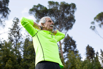 senior sportsman stretching during training in the park
