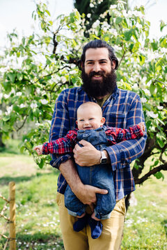 Bearded father with baby near tree in garden