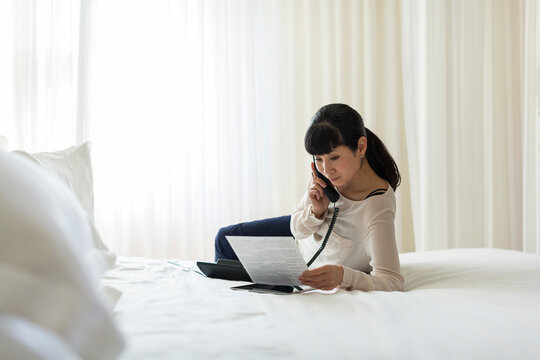 Businesswoman asking for service via phone in hotel room