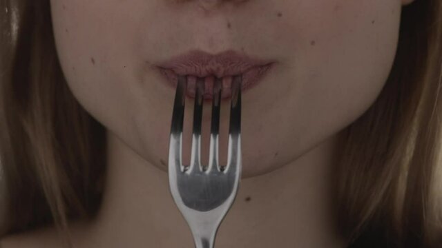 Close-up of mouth of beautiful young european unidentified woman eats from fork and chews a piece of meat. The concept of healthy tasty hearty food. Healthy food advertising