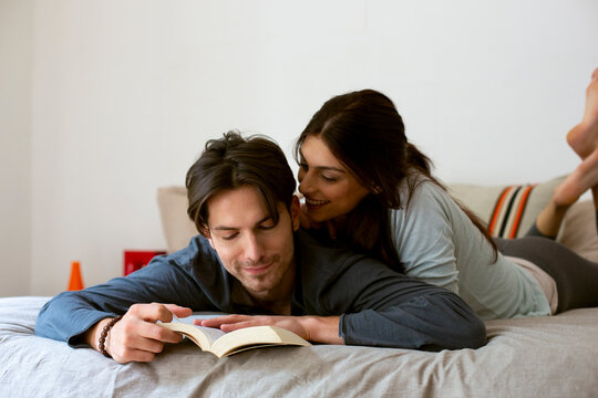 Happy couple reading book on bed