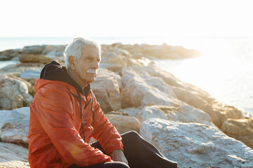 Inspired calm senior man resting on rocky coast