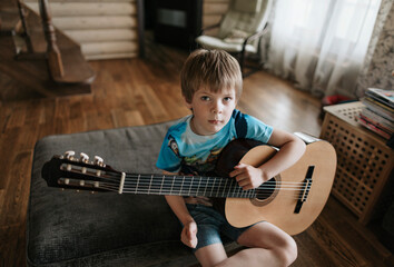 A young boy is learning to play the guitar.