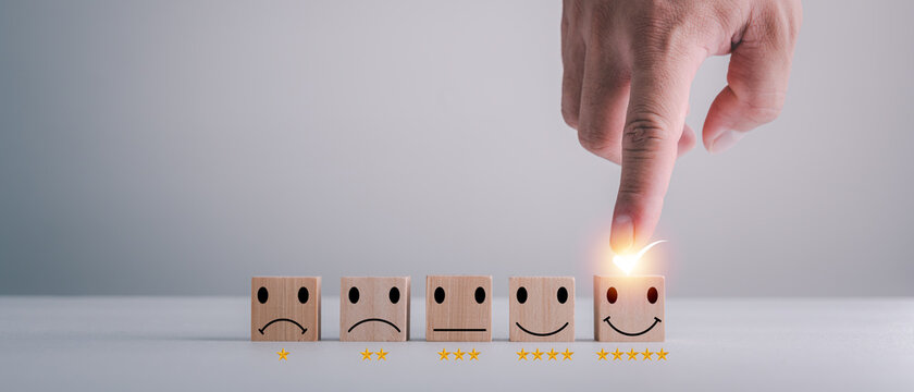 customer services best excellent business rating experience. Satisfaction survey concept. Hand of a businessman chooses a smiley face on wood block cube. 5 Star Satisfaction.