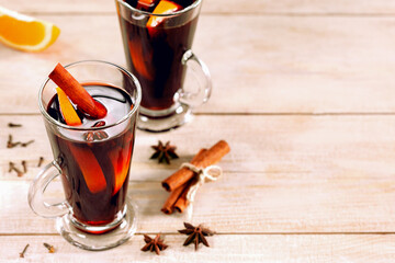 Hot mulled wine with spices and orange on wooden table with copy space.