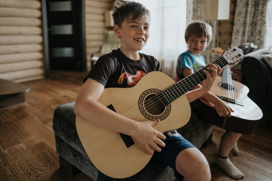A young boys is learning to play the guitar.