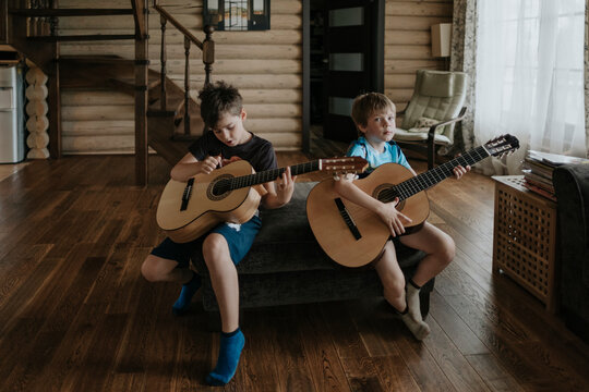 A young boys is learning to play the guitar.