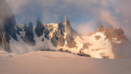 Alpinist standing in front of vast pointy mountain peaks