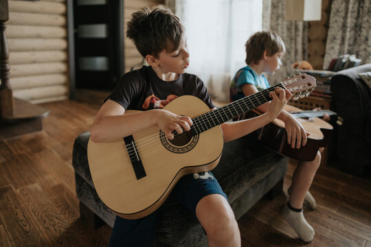 A young boys is learning to play the guitar.