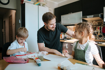 Young father teaches drawing his children.