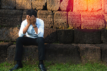 Asia you man sitting alone.He sitting alone beside old wall.man very sad and depressed.sad,alone,suicide,despair,sickness,photo health and disappointment concept.