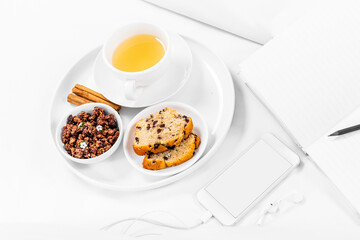 Breakfast tray on the bed, notebook, pencil, Smartphone, and earphones, white sheets. White background, copy space, mockup.