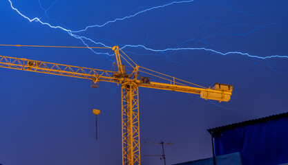 lightning over construction crane in the city