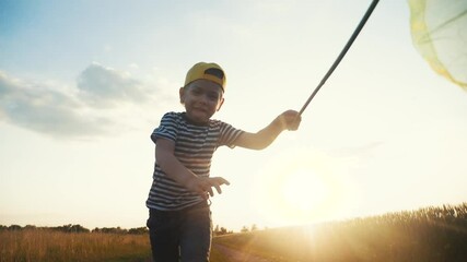 child run catching butterflies with a butterfly net in the park. happy family kid dream concept. boy run happy in the park with butterfly net silhouette. kid and butterfly net dream fun