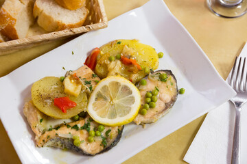 Delicious refreshing salmon with vegetable garnish and lemon sauce on white plate