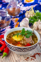bowl with turkey soup and red peppers with garlic on wooden background, close view 