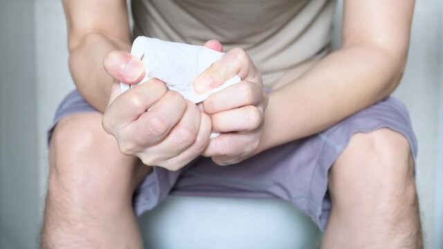 Man's hand, he holds a roll of toilet paper Going to the bathroom Toilet toilet background