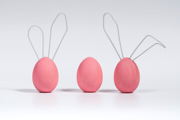Three pink Easter eggs, cute bunnies. Concept decoration for a Happy Easter. White isolated background with soft shadow.