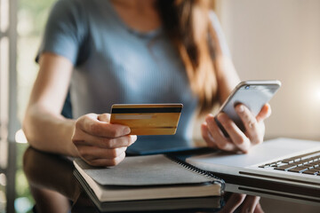 businesswoman hand using smart phone, tablet payments and holding credit card online shopping, omni channel, digital tablet docking keyboard computer at office in sun light.