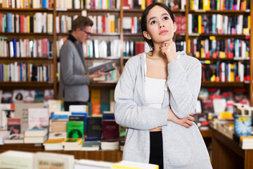Brazilian girl looking thoughtful and confused while visiting bookshop