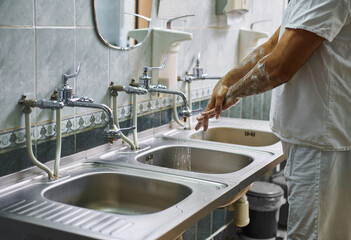 A surgeon in a white uniform is cleaning his hands with soapy water. Hand treatment before surgery.