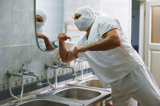 The surgeon turns off the water tap with his elbow after washing his hands. Hand treatment before surgery.