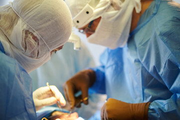 Surgery. Surgeons in special sterile clothing perform a surgical operation.