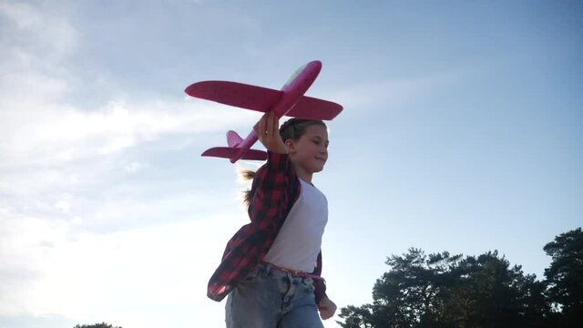 happy girl child run with an airplane. kid fun silhouette play plane. happy family dream freedom airplane concept. daughter kid run on wheat field at sunset holds in his hands dream toy aircraft