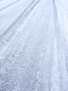 asphalt road covered with snow and tire tracks. roadway after snowfall