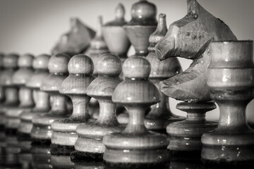 Wooden chess pieces stand on the board in the starting position before the battle.