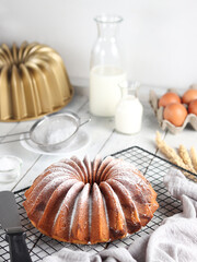 Homemade fresh Bundt Marble Cake or Marmer Cake with white sugar icing powder on the baking tray. White background. Selective focus.