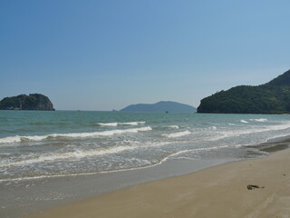 Wave splashing on the sandy beach, Fishing boat float in the sea with island in background  , Khao Sam Roi Yot National Park , Prachuap Khiri Khan , Thailand