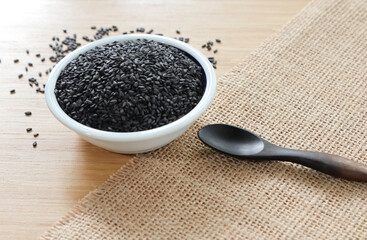black sesame in the cup with wooden spoon on the wooden table.