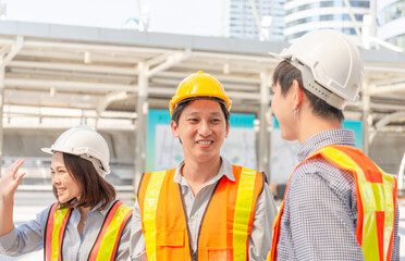 Smiling engineer happy to working together talking with team at outdoor construction site, Happiness and Teamwork concept.